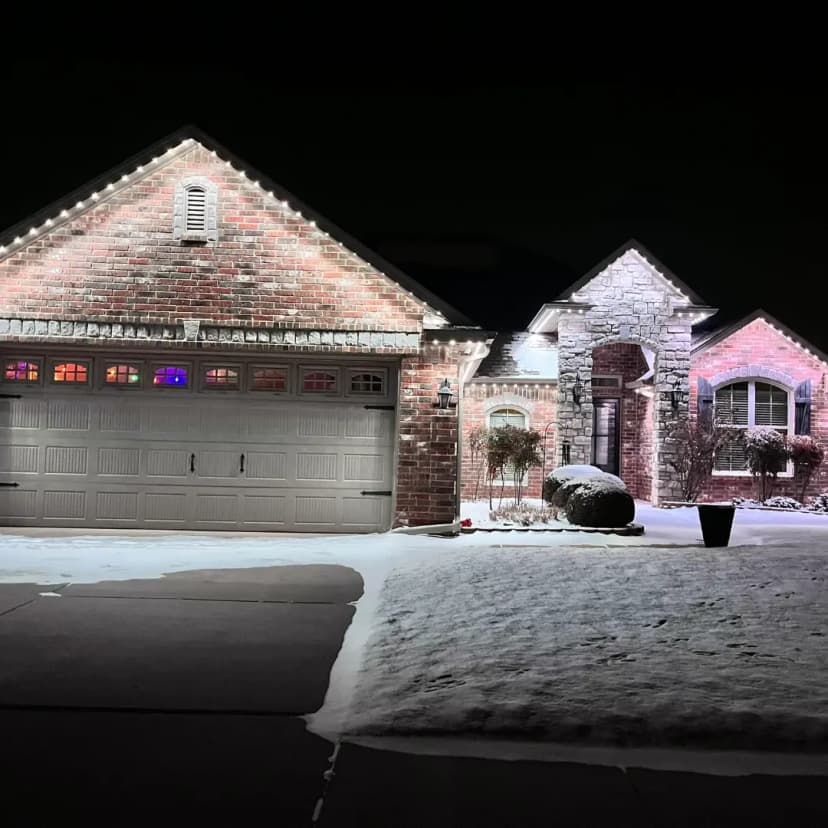 A home lit by Clear Lighting's efficient LED lighting in a cool mode at night, illuminating the exterior and snow.